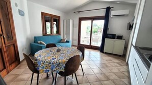 A compact kitchen with a dining table and chairs, a blue sofa, and a sliding glass door leading to an outdoor area. - Sea View Villa with Pool & Sunset Terrace | Private Parking | Badesi, Sardinia (Badesi)