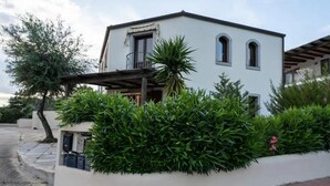 A modern two-story building with a balcony, surrounded by lush greenery and a paved driveway. - Sea View Villa with Pool & Sunset Terrace | Private Parking | Badesi, Sardinia (Badesi)