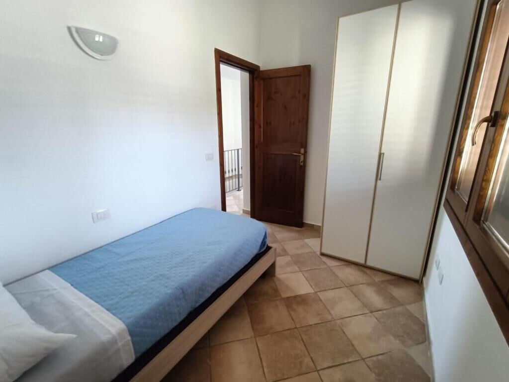 A bedroom with a bed, wardrobe, and a door leading to an outdoor balcony.