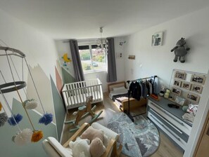 A baby room with a crib, rocking chair, and a wall-mounted baby swing.