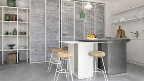 Cocina moderna con una isla central, taburetes de bar y un separador decorativo.
