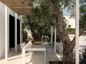 An outdoor dining area with a long table, chairs, and a bowl of fruit. - CocoTrullo (Ostuni)