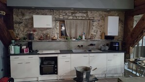 A kitchen with white cabinets, a stone wall, a sink, and a coffee maker. - A 2 pas des Étangs, Calme et Spacieux Bienvenue a Peyriac de mer (Peyriac-de-Mer)