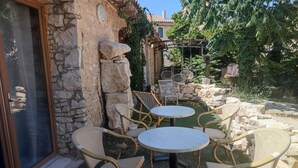 An outdoor patio with wicker furniture and stone walls. - A 2 pas des Étangs, Calme et Spacieux Bienvenue a Peyriac de mer (Peyriac-de-Mer)