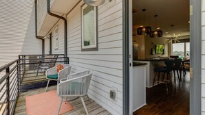 A modern kitchen with bar stools, a dining table, and pendant lighting. - Melrose Townhome Balcony|Walkable to Coffee & Eats (Berry Hill)