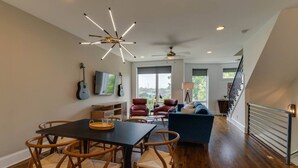 A spacious living area with a dining table, chairs, a sofa, and a TV. - Melrose Townhome Balcony|Walkable to Coffee & Eats (Berry Hill)