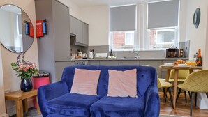 A modern living room with a blue sofa, a wooden coffee table, and a kitchen in the background. - Routh Retreat (Whitby)