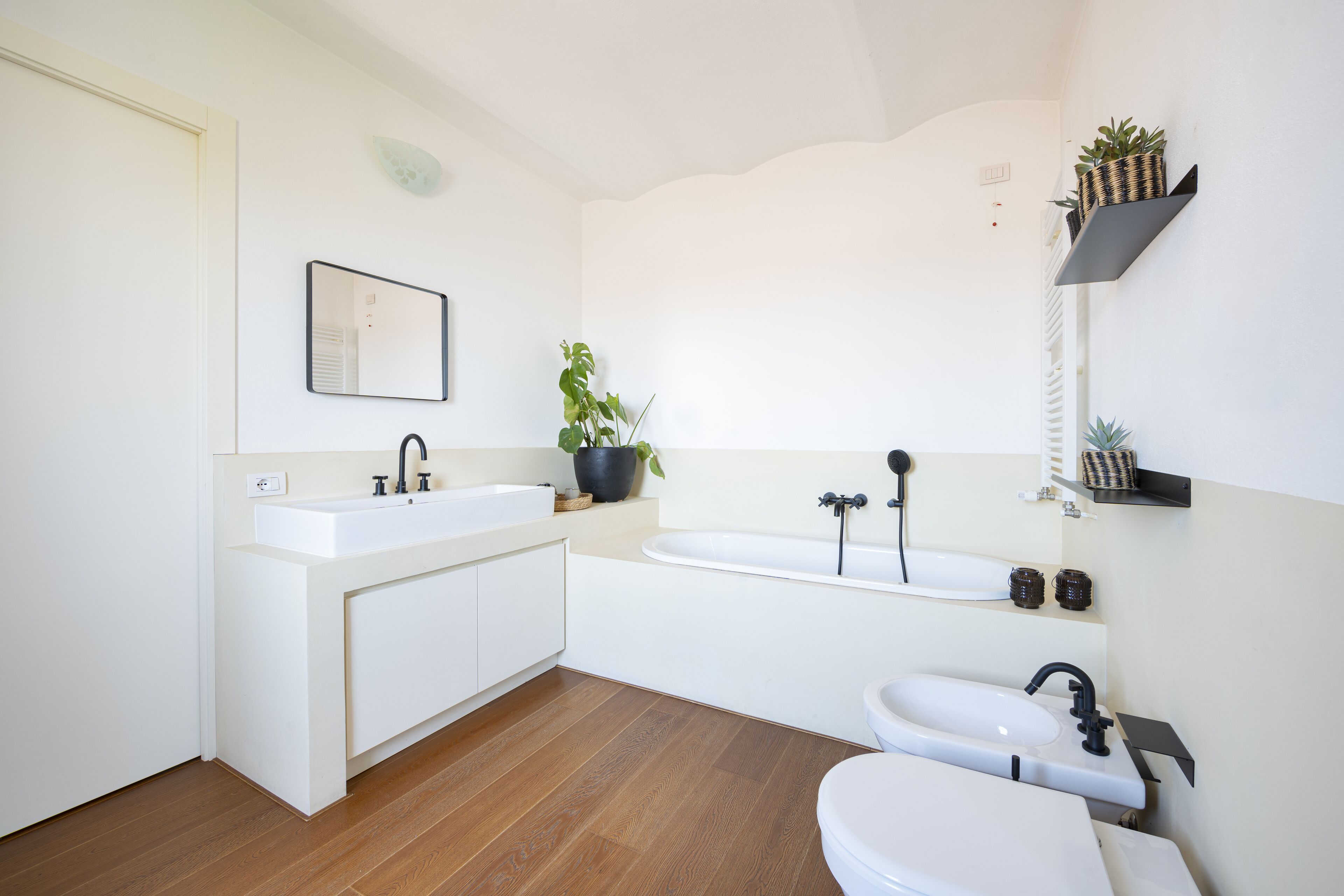A modern bathroom with a white vanity, a bathtub, and a toilet.
