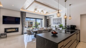 Een moderne keuken met een groot eiland, hanglampen en een eetgedeelte met uitzicht.