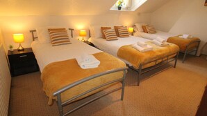 A hotel room with two beds, each with a headboard, and a small table between them. There are lamps on either side of the beds, and a window above the beds. - Lundwood House (Barnsley)