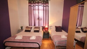 A twin room with two beds, a mirror, a nightstand, and a window with curtains. - Lundwood House (Barnsley)