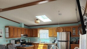 A spacious kitchen with wooden cabinets, a dining area with a wooden table and chairs, and a small bar area with stools. - Comfortable cottage in gated community, 5 mins to OC and Assateague (Berlin)
