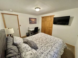 Un dormitorio con cama, escritorio, silla, televisor y armario.