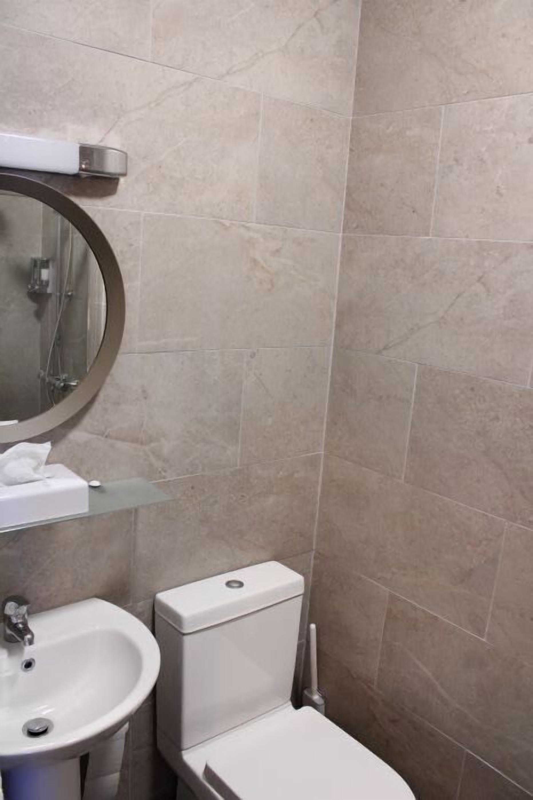A bathroom with a toilet, sink, and a mirror.