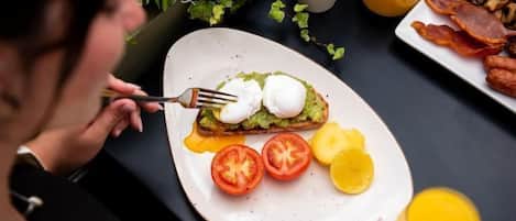 A breakfast plate with eggs, avocado, tomatoes, and lemon slices.