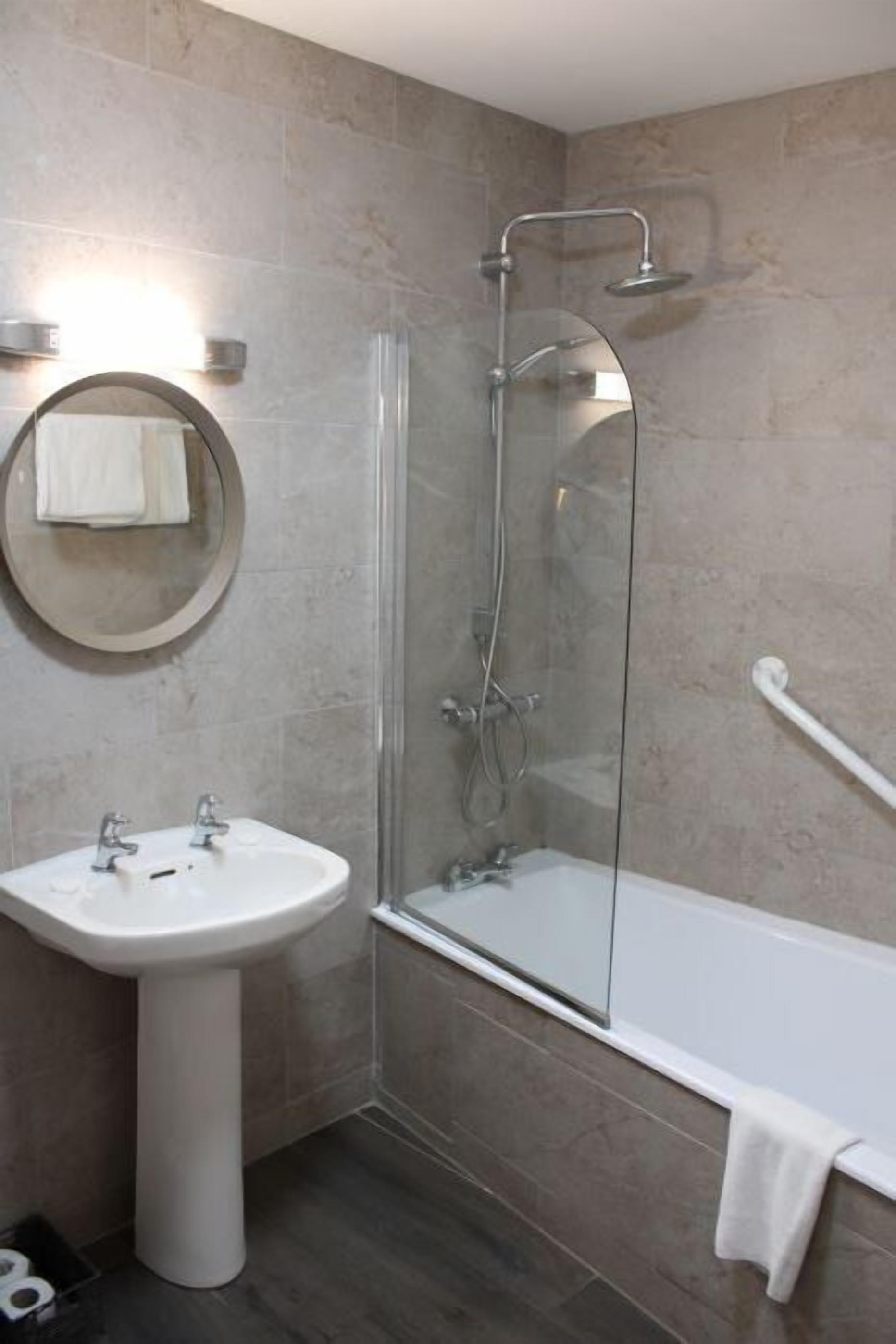 Une salle de bain avec un lavabo sur colonne, une douche à parois de verre et une baignoire blanche.