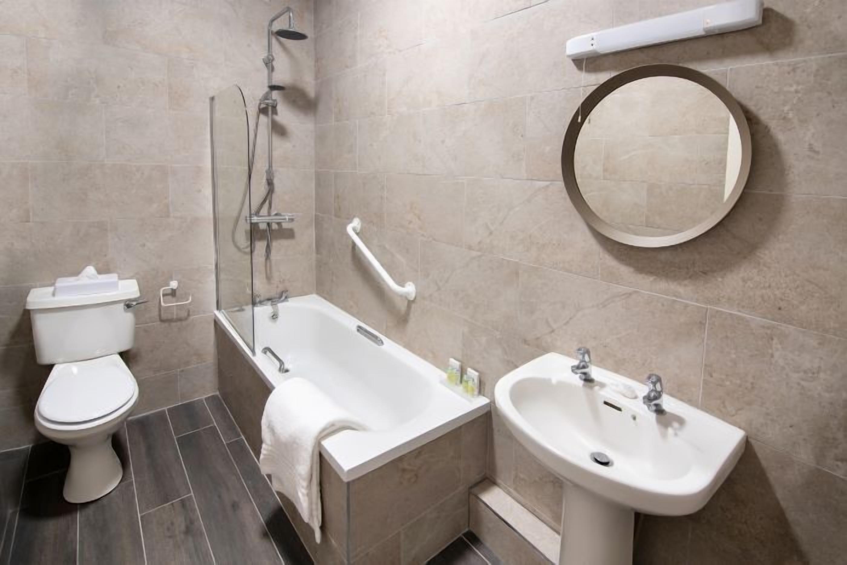 Une salle de bain moderne équipée de toilettes, d’une baignoire et d’un lavabo.