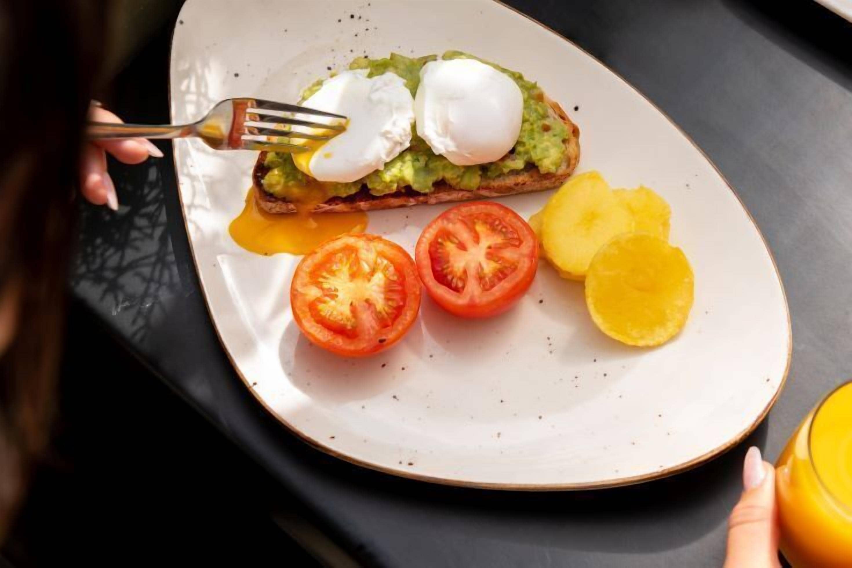 A plate with a poached egg on toast, tomato slices, and a slice of pineapple.