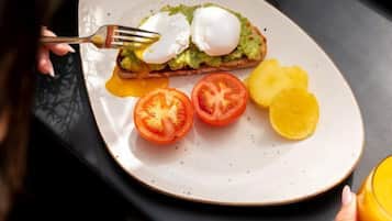 Une assiette avec un œuf poché sur une tranche de pain grillé, des tranches de tomate et une tranche d’ananas.