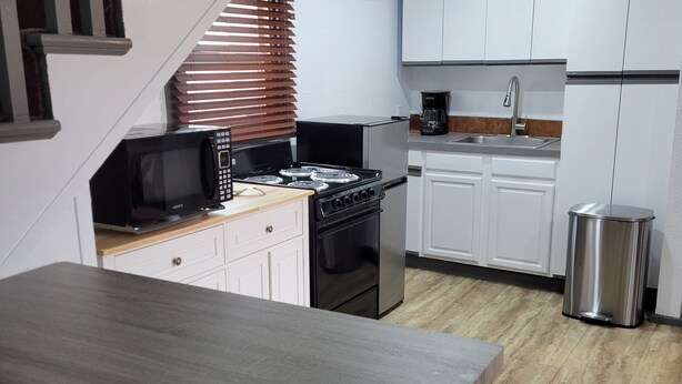Una cocina moderna con armarios blancos, un lavamanos de acero inoxidable, una estufa y un microondas.