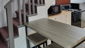 Una escalera con barandillas de madera que conduce a una zona de cocina con microondas, estufa y armarios.