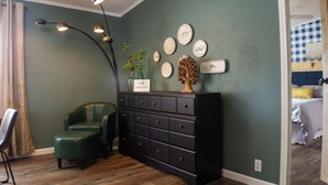 A room with a green wall, a black dresser with multiple drawers, a green chair, and a plant on the dresser. - Family friendly bungalow with big yard and deck, close to town (Deckerville)