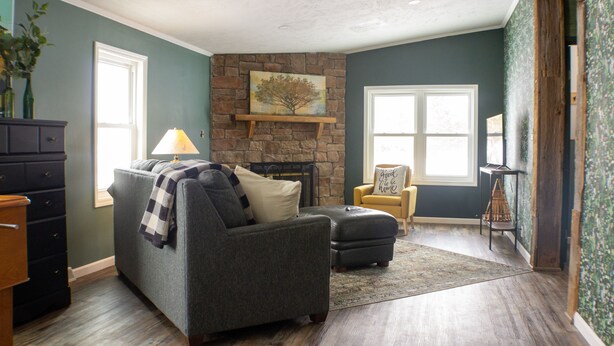 A living room with a fireplace, a sofa, a chair, and a rug. - Family friendly bungalow with big yard and deck, close to town (Deckerville)