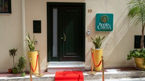 A hotel entrance with a red carpet, potted plants, and a sign for Borgia La Chiusa Holiday House. - Borgo La Chiusa (Cinisi)
