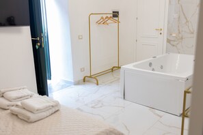 A modern bathroom with a white bathtub, a gold towel rack, and a neatly folded set of towels on the floor. - Borgo La Chiusa (Cinisi)