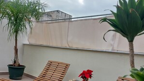A rooftop terrace with wooden lounge chairs, a small table, and potted plants. - Borgo La Chiusa (Cinisi)