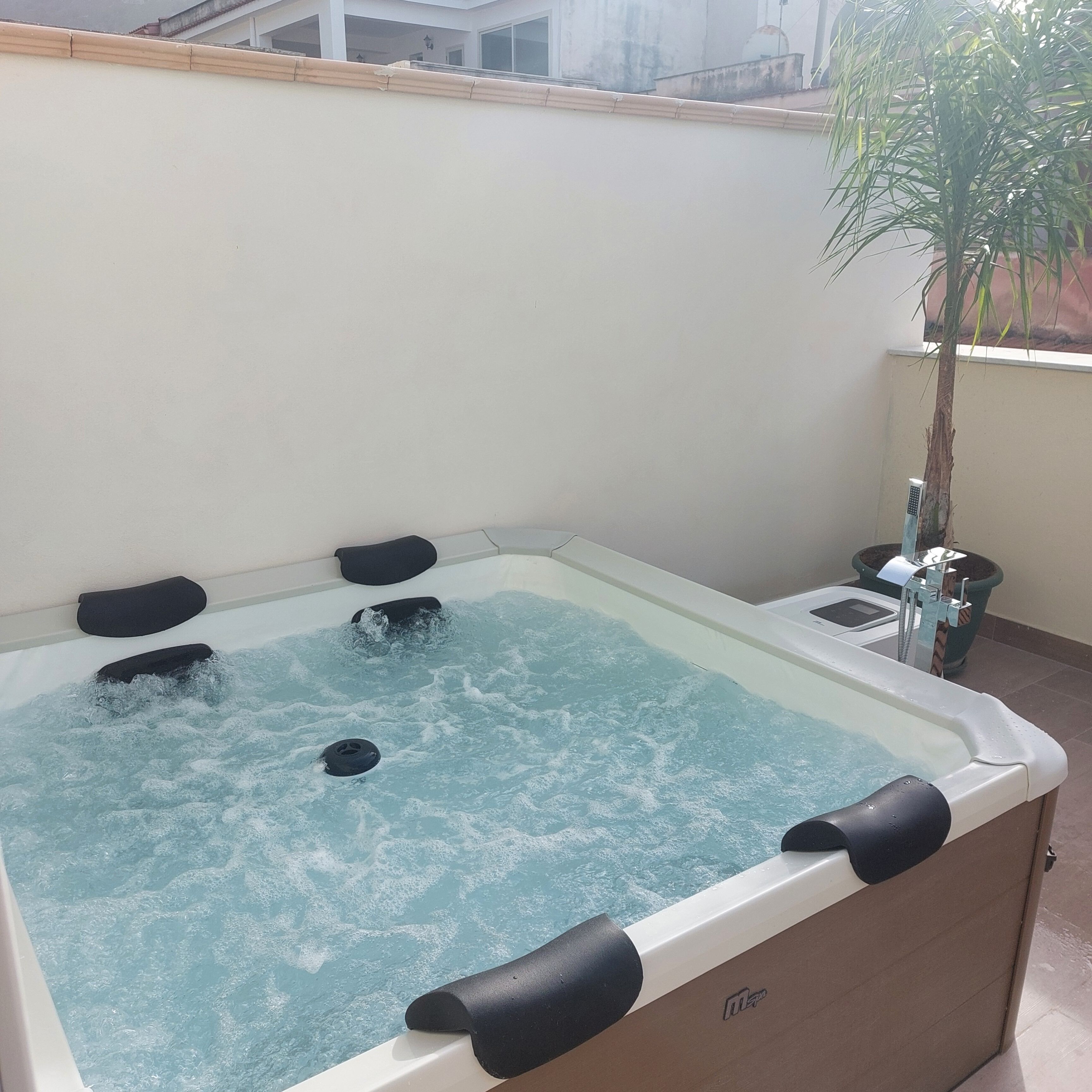 Una bañera de hidromasaje con cuatro asientos negros y un panel de control en el lateral.