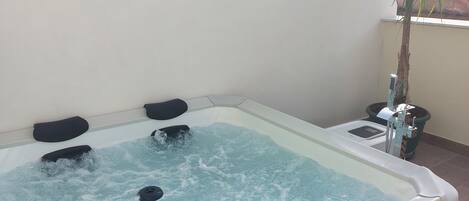 Una bañera de hidromasaje con cuatro asientos negros y un panel de control en el lateral.
