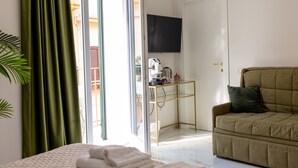 A room with a bed, a sofa, a TV, and a desk with a computer. - Borgo La Chiusa (Cinisi)