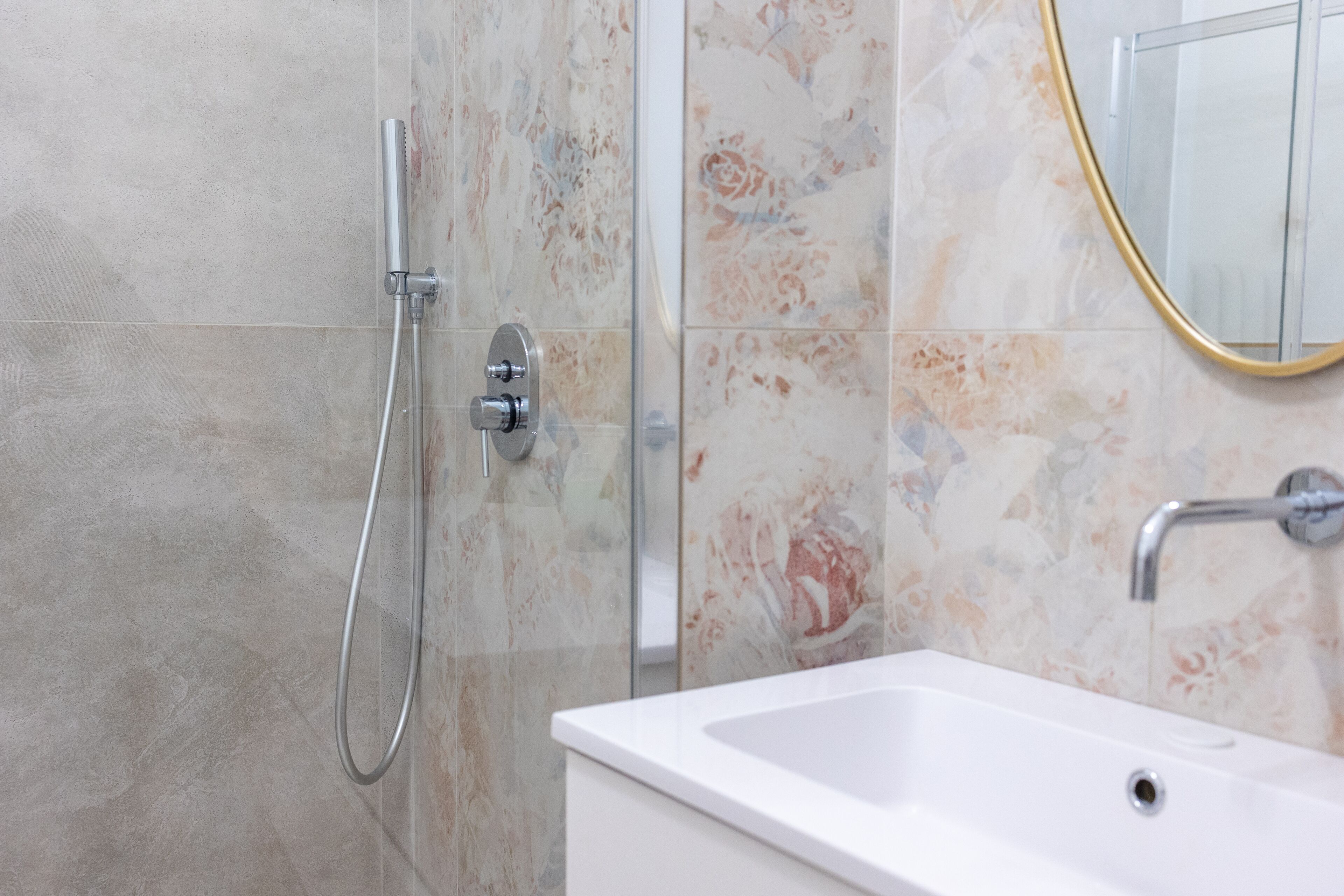 A bathroom with a shower, a sink, and a mirror.