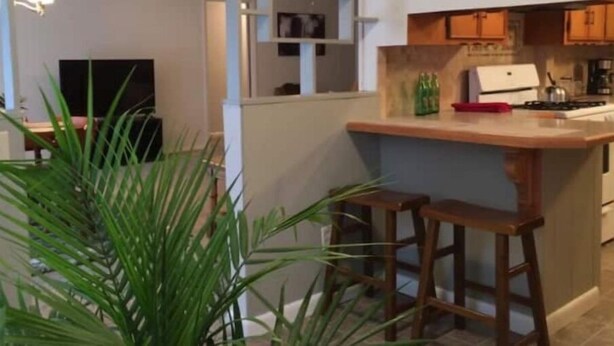 Una cocina moderna con una isla de madera, taburetes de bar y un horno empotrado.