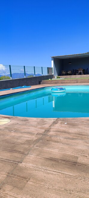 A swimming pool with a wooden deck, a covered seating area with chairs, and a view of mountains in the background. - Villa with Private Pool and Douro Valley Views – 10 Minutes from Peso da Régua (Peso da Régua)