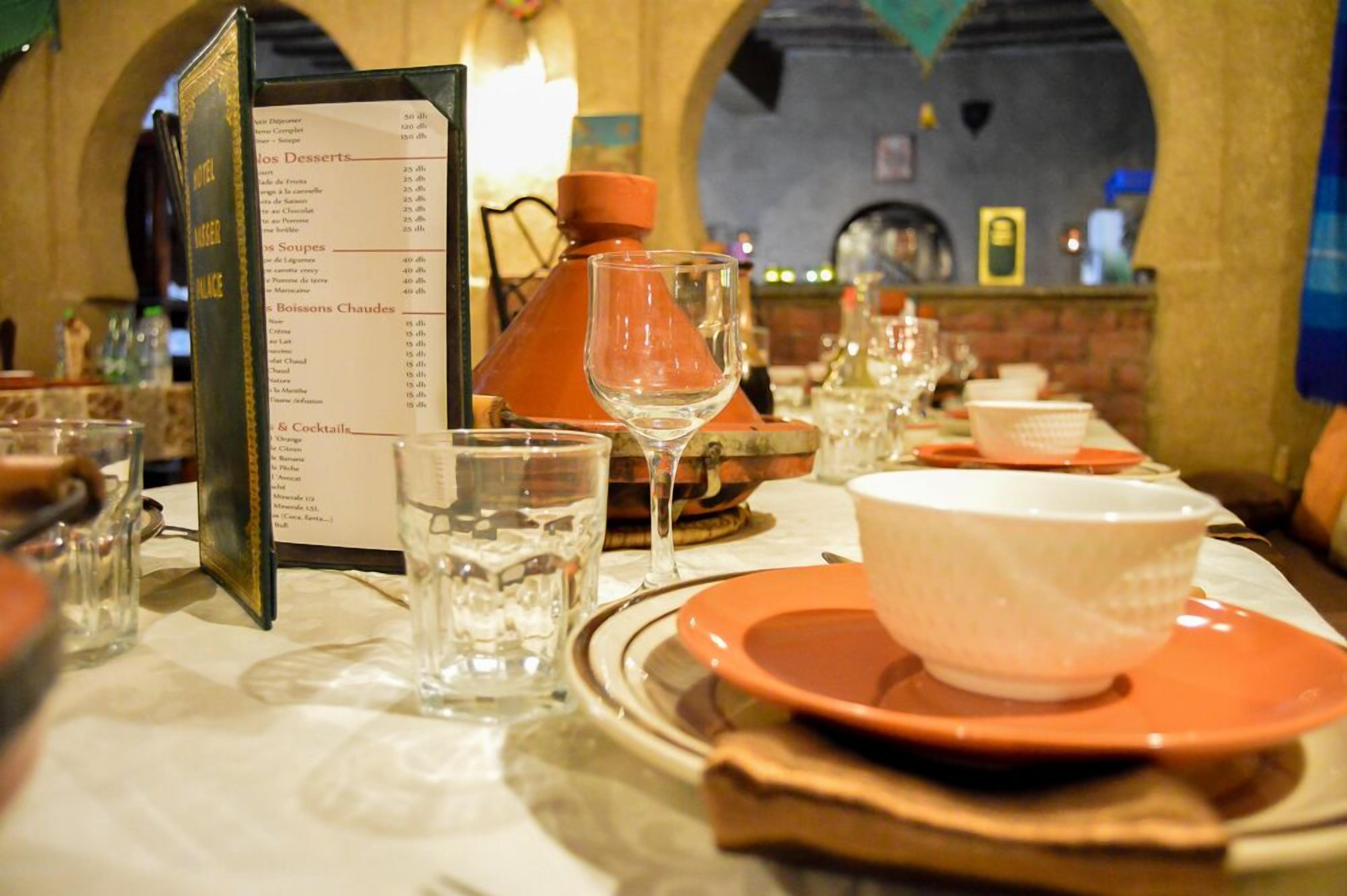 Un restaurante con un menú, copas de vino y platos sobre la mesa.