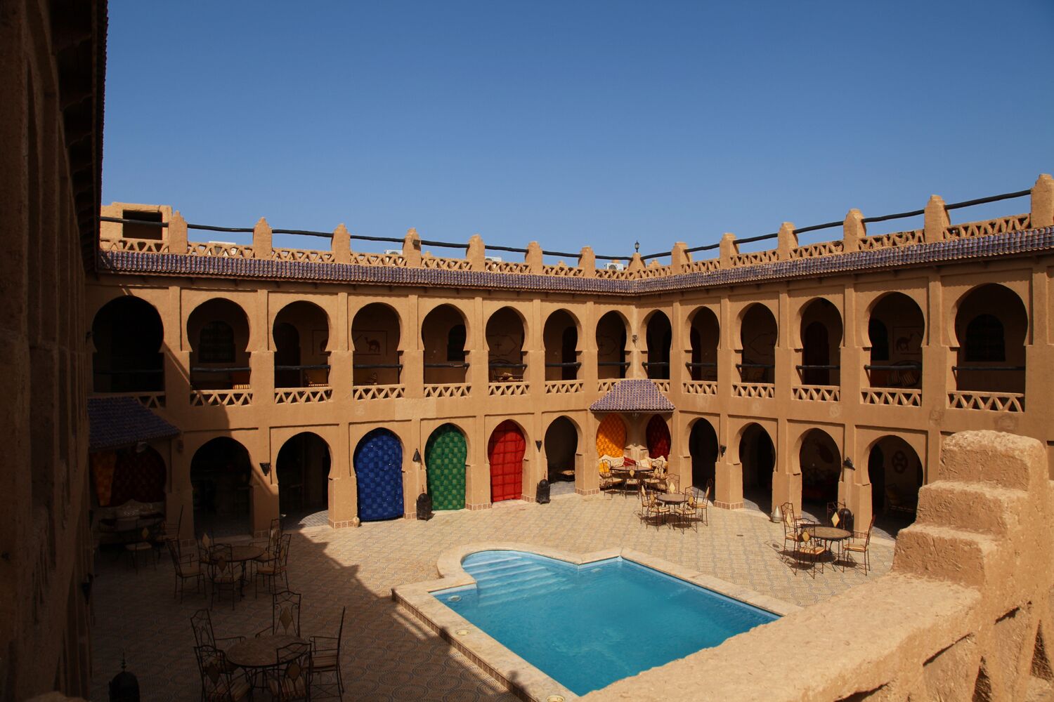 Un patio con piscina, varios arcos y mobiliario para exteriores.