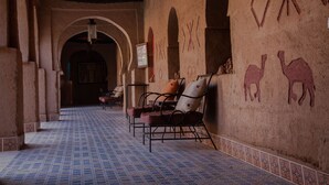 Un couloir doté d’un sol carrelé, d’arches et d’un mur orné de motifs géométriques et de motifs représentant des chameaux.