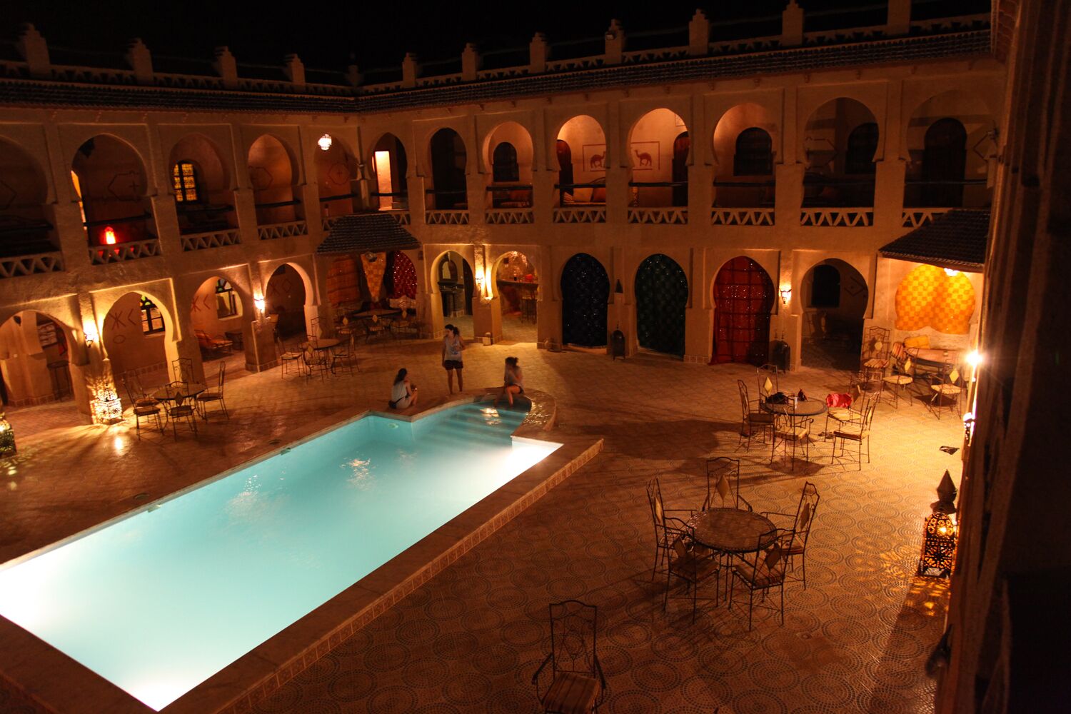 Un patio con piscina, mobiliario exterior y puertas abovedadas.