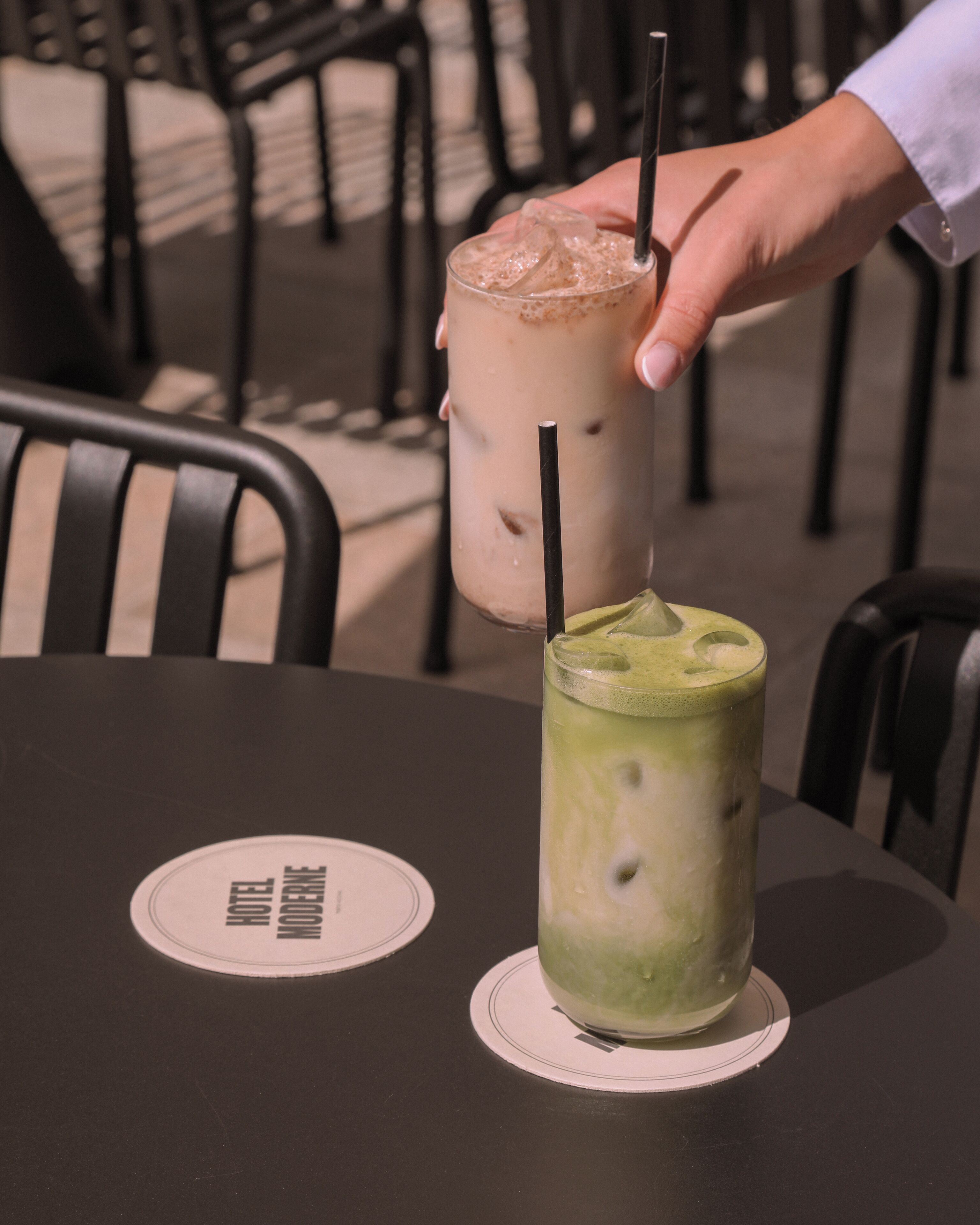 Two drinks on a table with a coaster that has a logo.