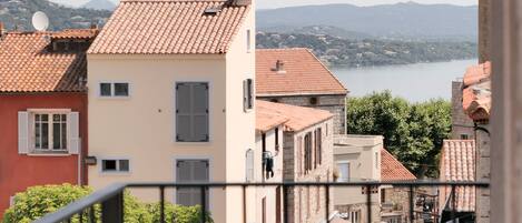 A view of a street with buildings, a body of water, and mountains in the background.