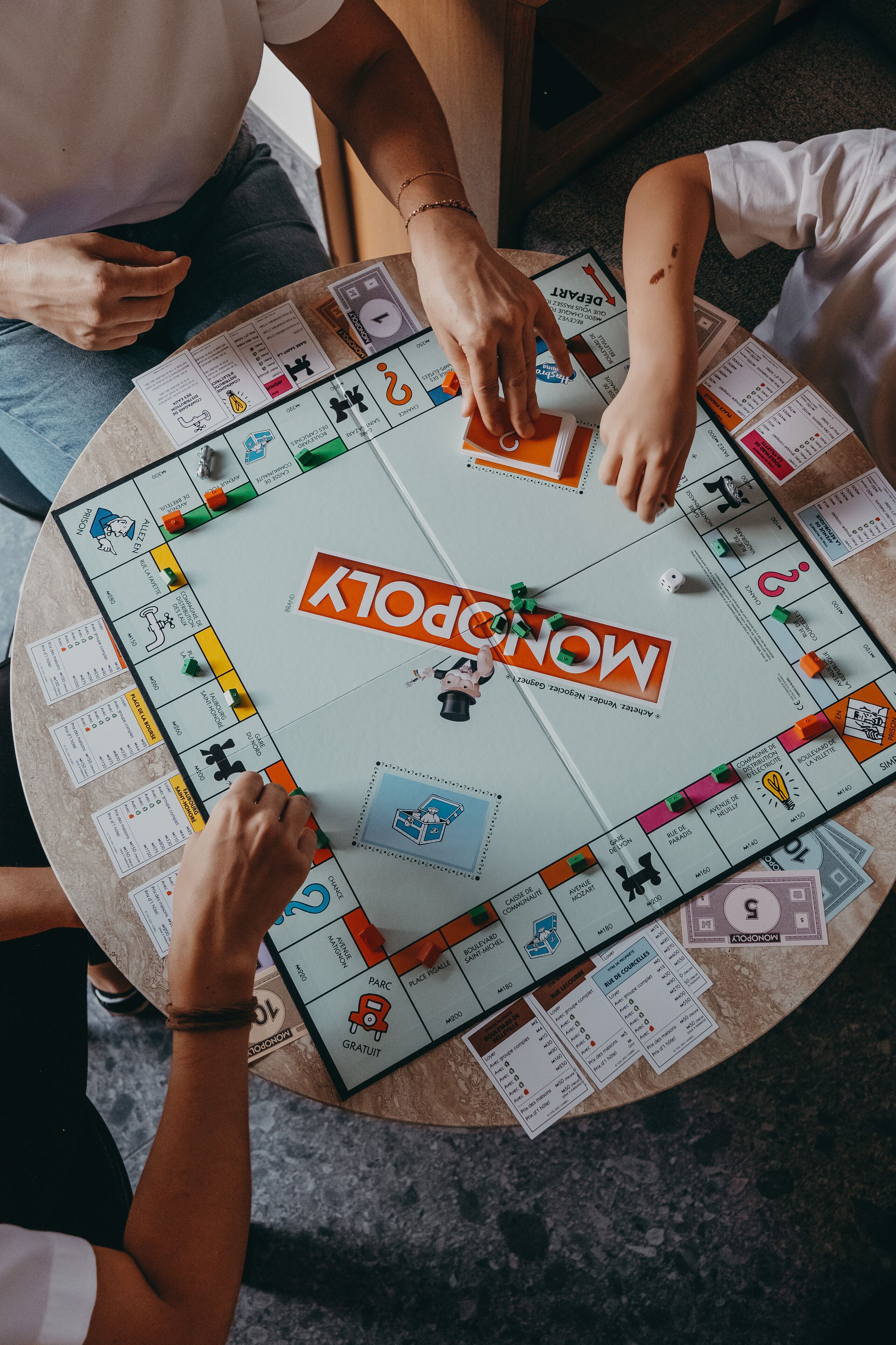 A group of people playing a board game around a round table.