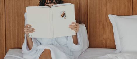 Una persona con bata blanca leyendo un libro en una cama, con una bandeja de alimentos para el desayuno.