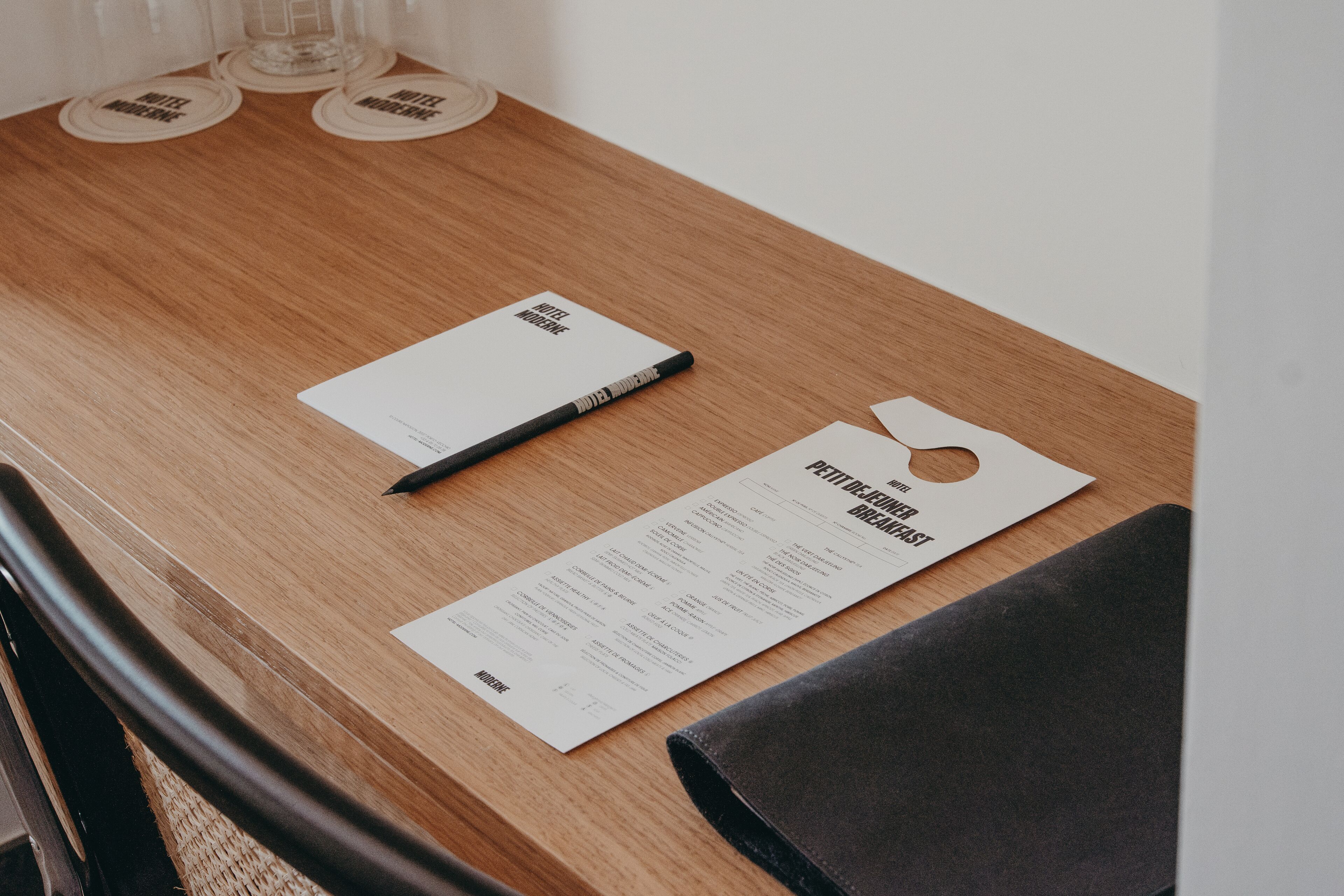 Una mesa de madera con un menú, un bolígrafo y posavasos.