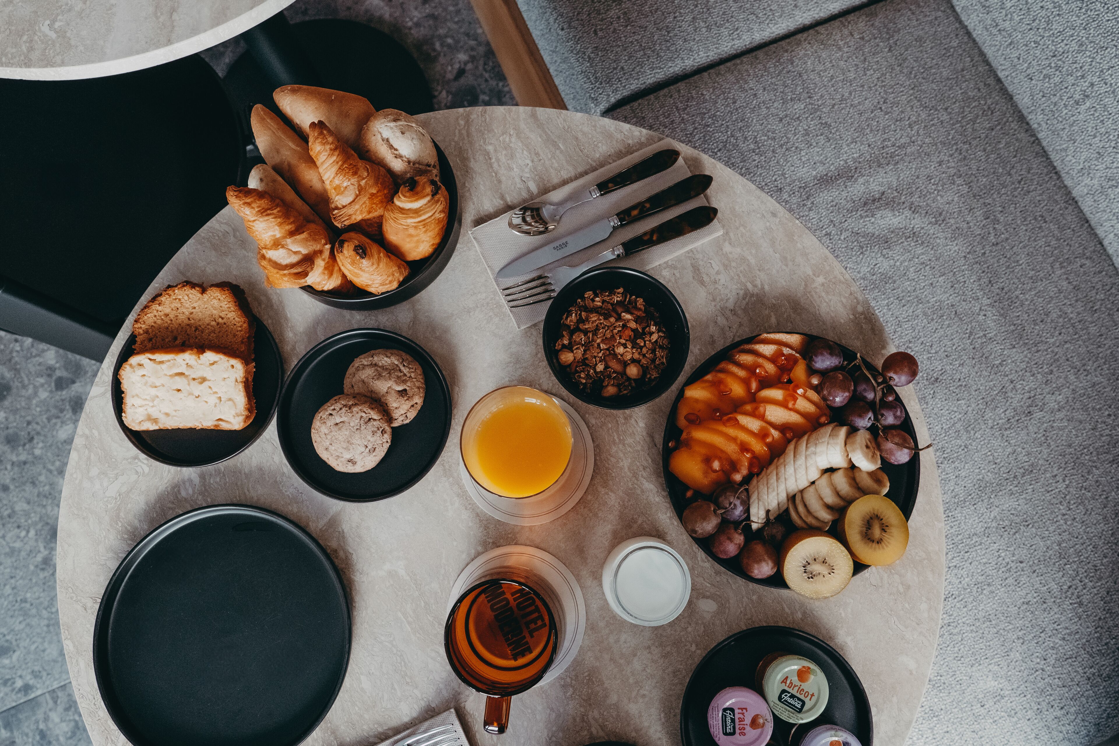 Een ontbijttafel met croissants, brood, fruit en drankjes.