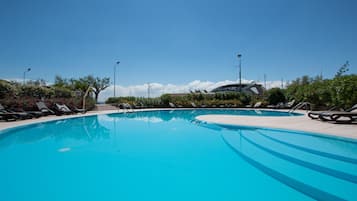 Relax by the serene pool surrounded by lounge chairs and lush greenery.