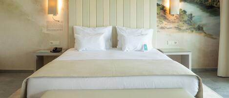 A hotel room with a large bed, two bedside tables, a nightstand, a wall-mounted lamp, and a mural.