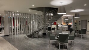 A modern interior with a curved staircase, seating area, and bar/lounge. - Vila Gale Collection Hotel Monte do Vilar (Beja)