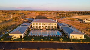 A large building with a swimming pool, surrounded by a landscaped lawn and multiple smaller buildings. - Vila Gale Collection Hotel Monte do Vilar (Beja)